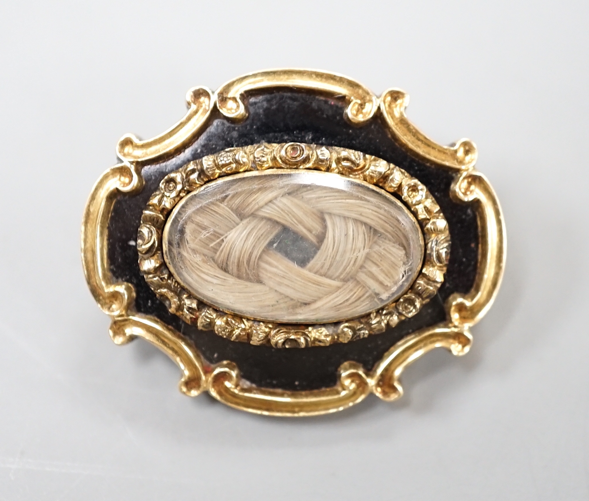 An early Victorian yellow metal, black enamel and plaited hair mourning brooch, inscribed verso, 'Revd. JWH Marshall Obt 23rd March, 1841 at 38', 27mm.